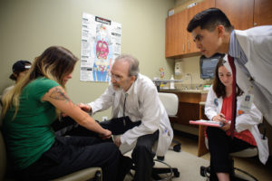 Richard P. Usatine, M.D., and medical students Mikaela Miller and Tommy Pham examine a patient.
